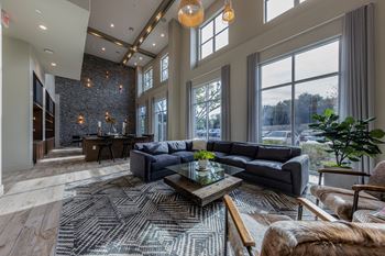 a living room with couches and a coffee table in front of large windows at The Monroe Apartments, Austin, TX